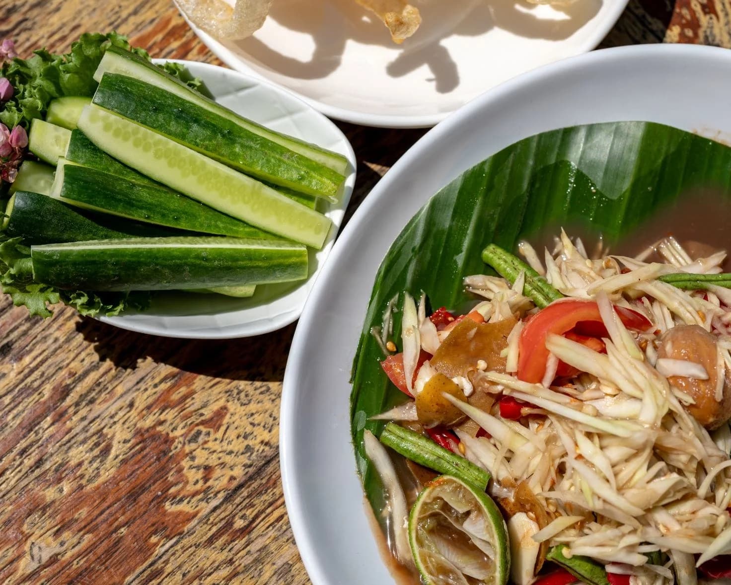 Green papaya som tum plated on a banana leaf with fresh vegetables at SOHO Pool Club, Phuket