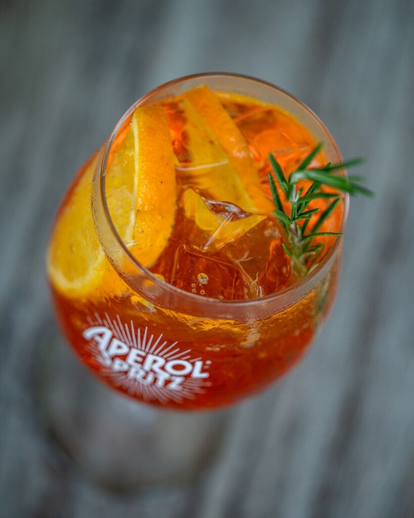 Close-up of Aperol Spritz cocktail with orange slices and rosemary garnish at SOHO Pool Club Phuket