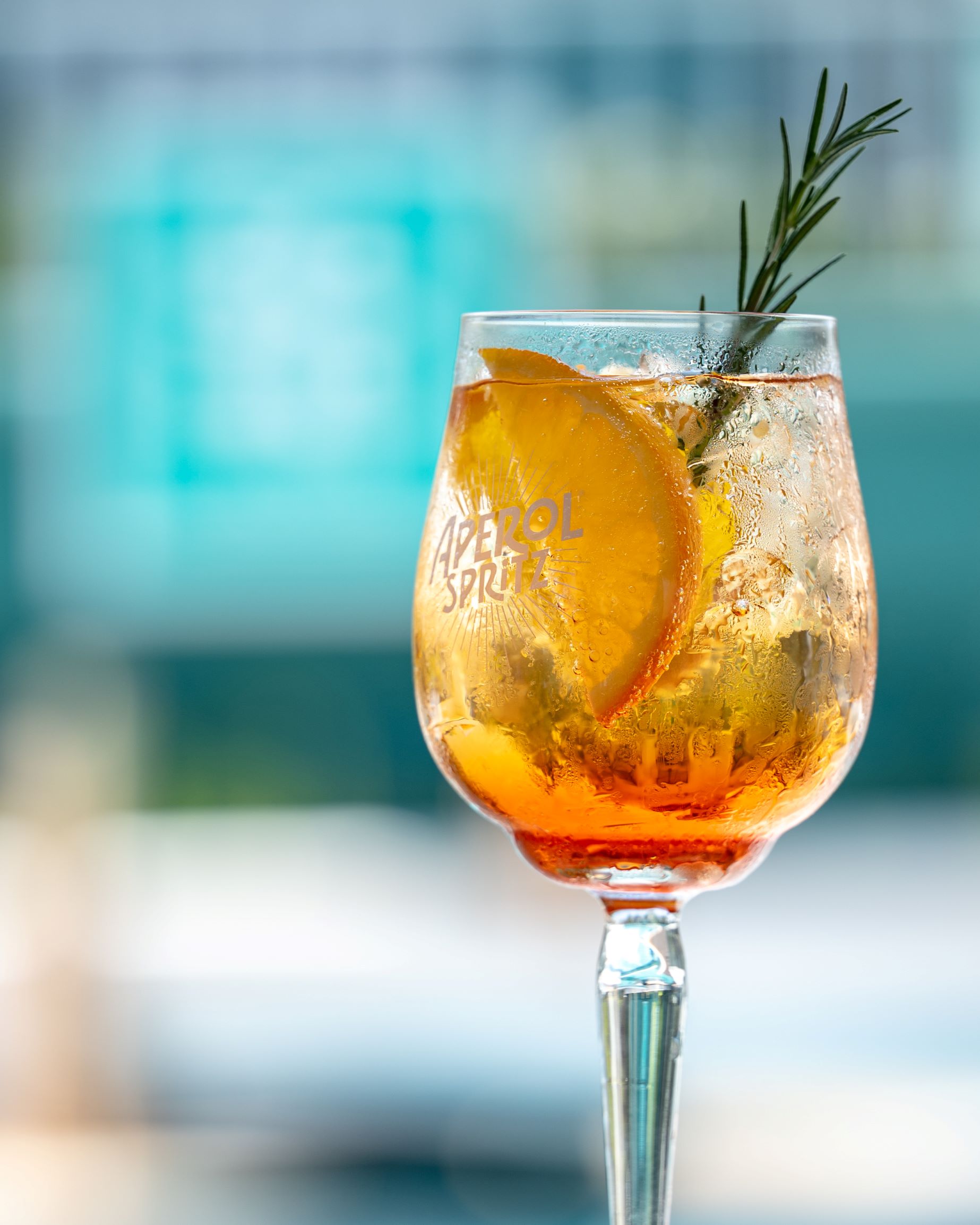 Refreshing Aperol Spritz cocktail with orange slice and rosemary served by the pool at SOHO Pool Club Phuket