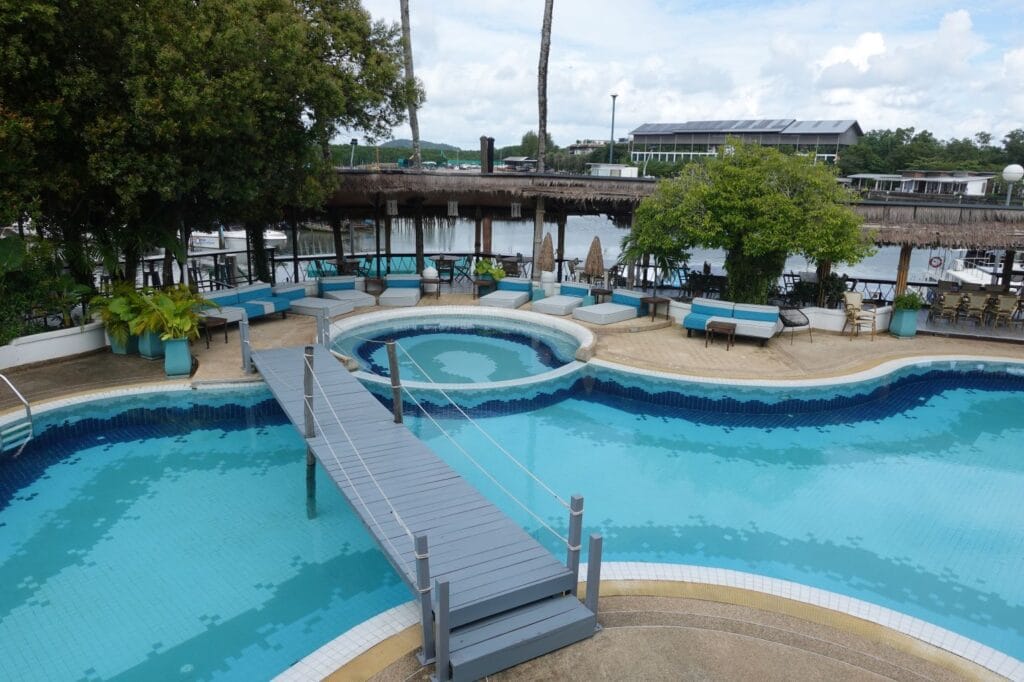 Aerial view of the SOHO Pool Club Phuket pool area with sunbeds and marina backdrop