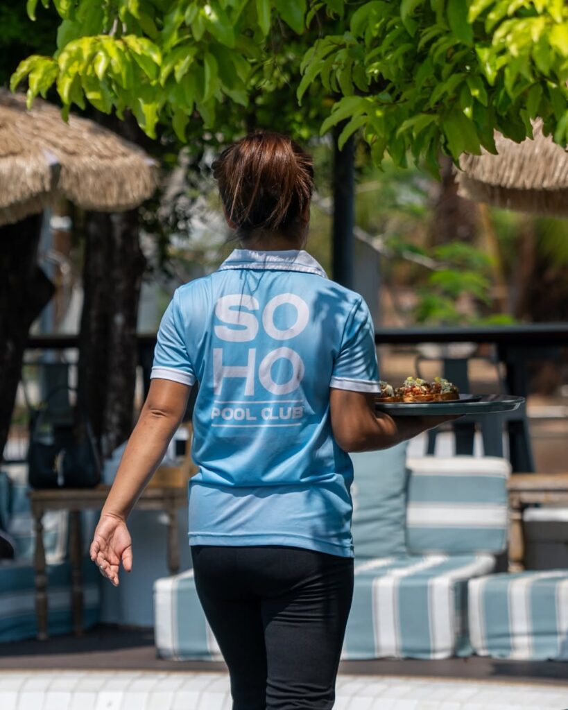 Waitress in SOHO Pool Club uniform serving food beside the pool in Phuket